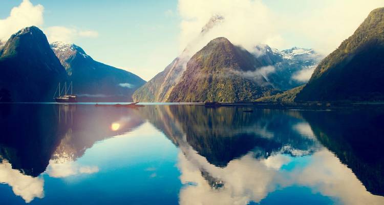 Reflection of mountains in a calm lake with a single boat.