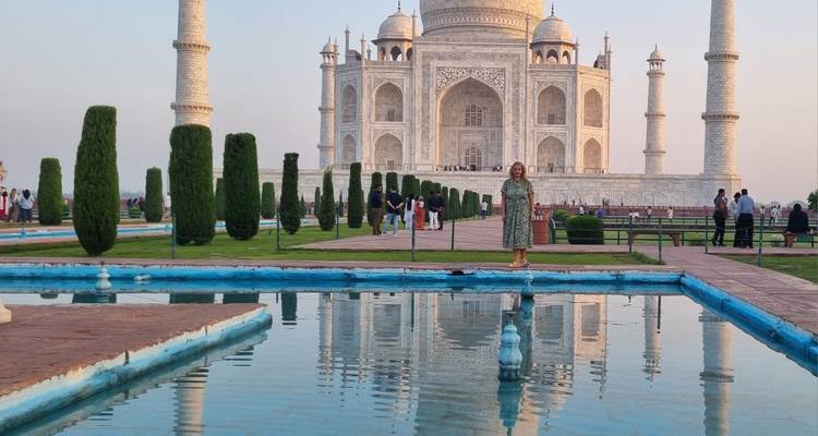 Un visiteur se tient à côté des bassins de réflexion devant le Taj Mahal au crépuscule.