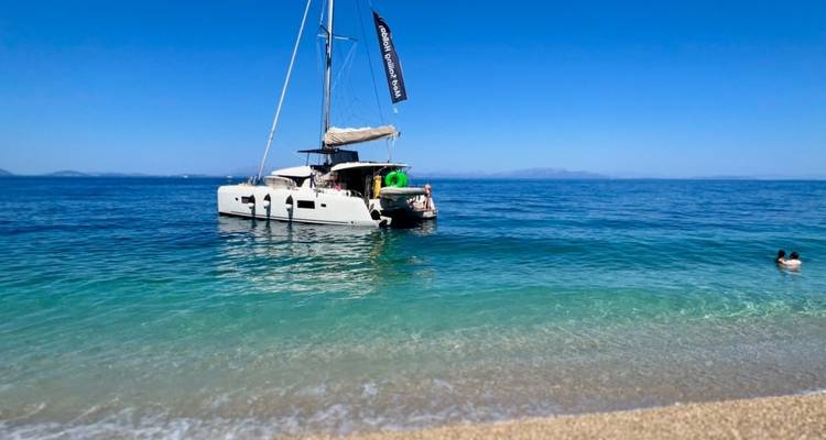 Voilier à l'ancre dans une eau bleue claire près d'une plage.