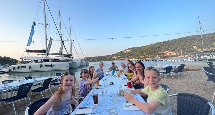 Des gens qui dînent à une longue table au bord de la mer.