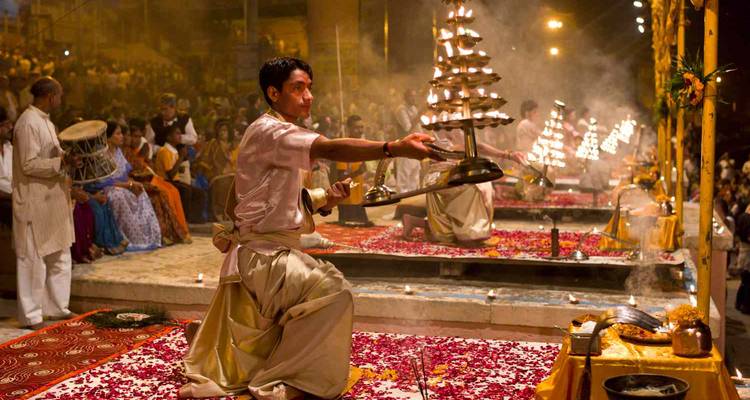 Persona realizando un ritual tradicional en un entorno abarrotado.