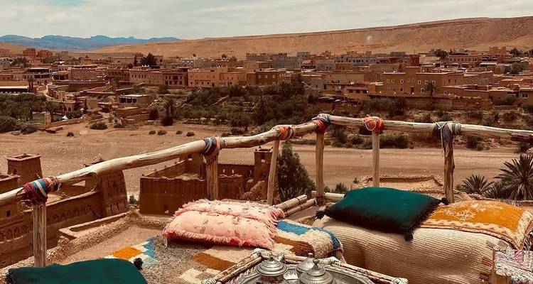 Vue depuis une terrasse de toit surplombant une ville du désert avec une architecture traditionnelle.