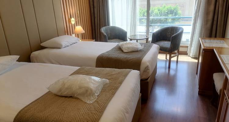 Chambre d'hôtel avec lits jumeaux et grandes fenêtres.