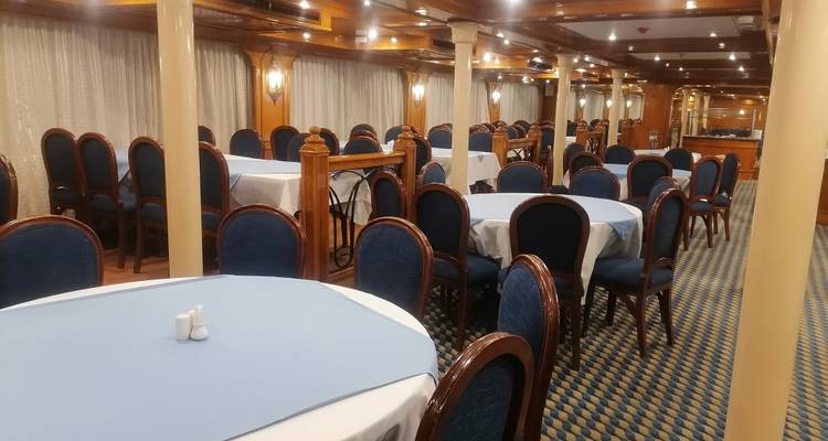 Salle à manger avec tables dressées pour un repas.
