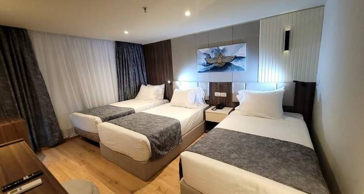 Chambre d'hôtel avec trois lits et décoration minimaliste.