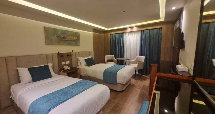 Chambre d'hôtel avec deux lits et un coin salon.