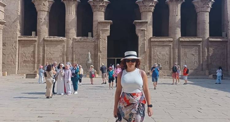 Een vrouw poseert voor de ingang van een oude tempel.