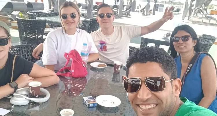 Groep mensen die aan een tafel buiten zitten en glimlachen.