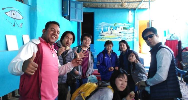 Groepsfoto van toeristen die vrolijk poseren in een kleurrijk gebouw.