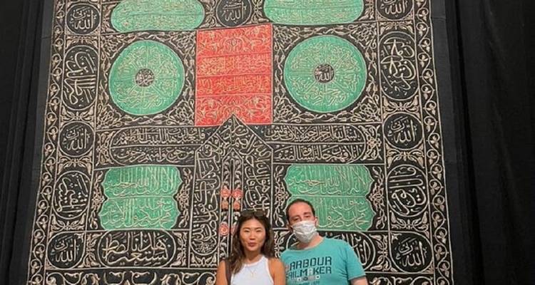 Dos personas frente a un textil decorado.