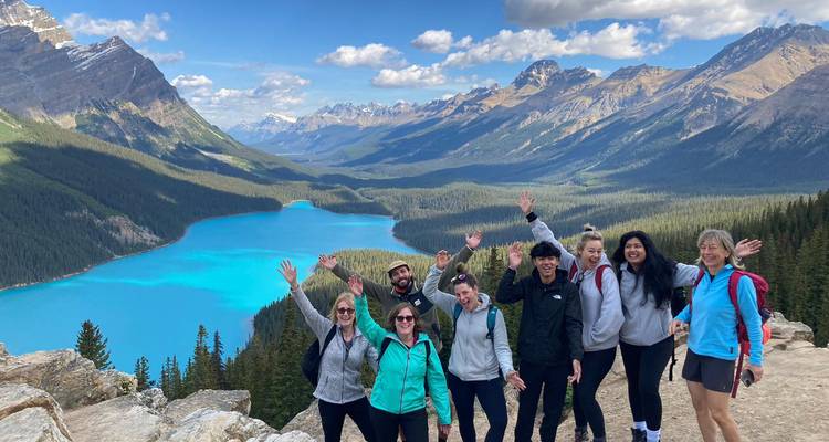 Group posing above a bright blue lake in a mountain setting.