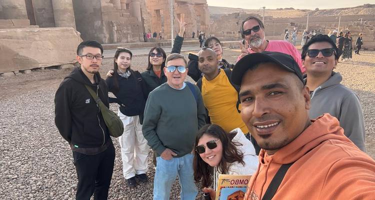 Internationale trekking groep poserend op een grindvlakte met oude stenen ruïnes op de achtergrond onder de late middagzon