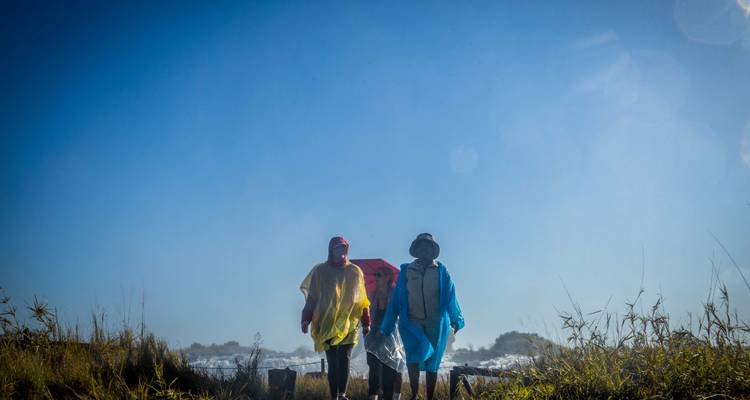 Three people in rain gear walking near Victoria Falls.