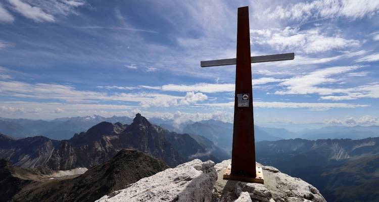 Bergtop met een kruis tegen een blauwe lucht op de achtergrond.