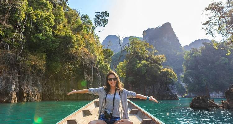 Mujer disfrutando de un paseo en barco en un paisaje tropical.