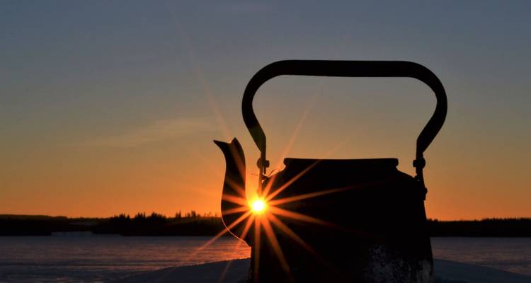 Hintergrundbeleuchtete Silhouette eines Kessels mit Sonnenstrahlen-Effekt.