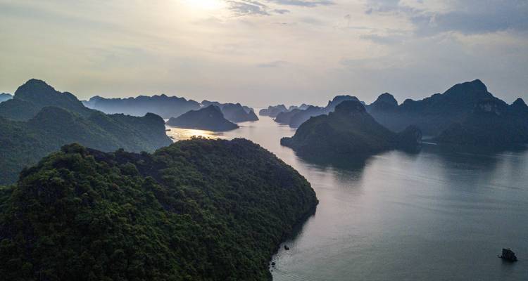 Vue aérienne de la baie d'Halong avec des îles lointaines et des eaux calmes.