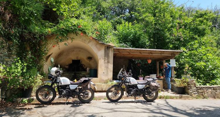 Two motorcycles parked next to a rustic shelter.
