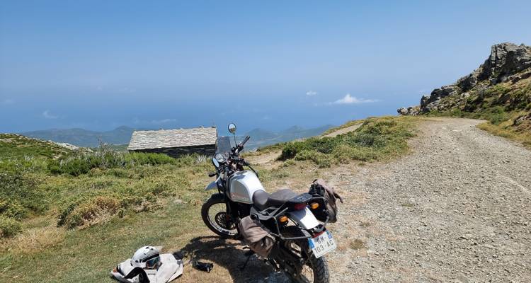 Motorcycle parked on a mountainous trail with an ocean view.