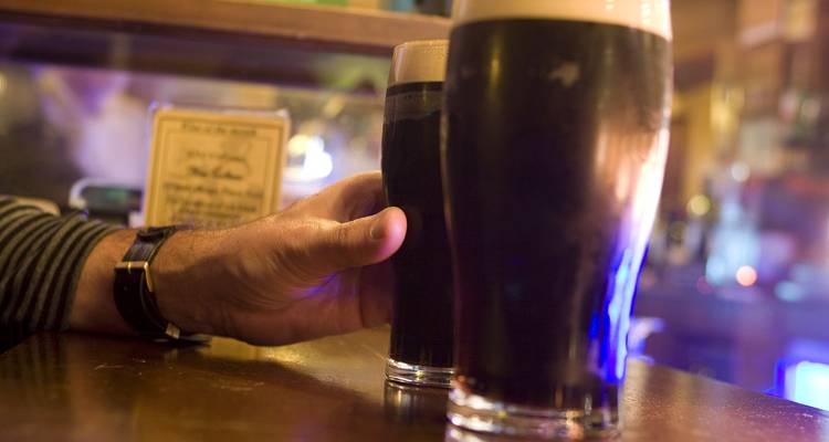 Close-up van een hand die een pint donker Iers stout vasthoudt in een gezellige pub