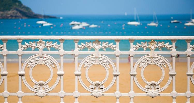 Sierlijke leuningen aan de kust met boten in de verte.