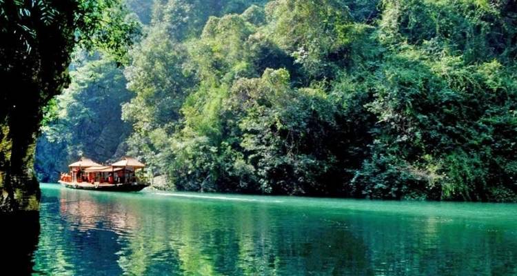 Traditional boat on a calm river surrounded by lush greenery.