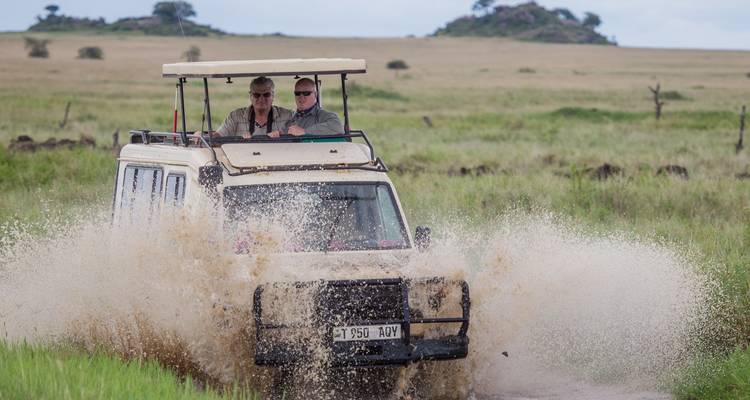 Safarivoertuig dat door een waterplas rijdt
