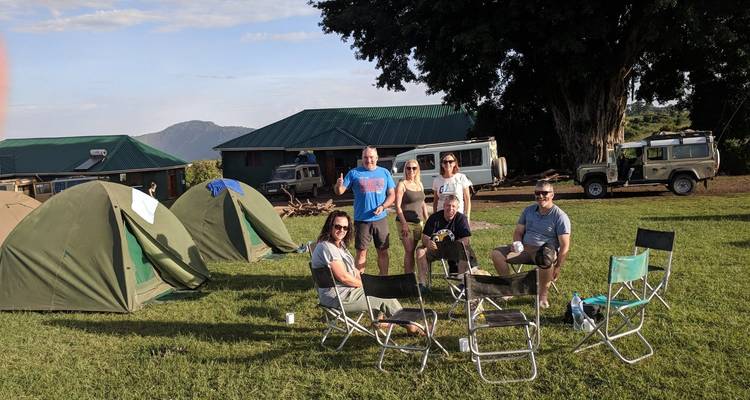 Groep mensen die genieten van een camping met stoelen en hutten.