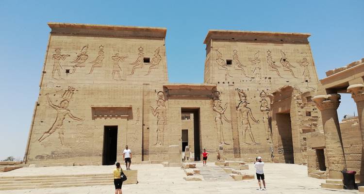Visiteurs à l'entrée d'un temple ancien avec de grandes sculptures.