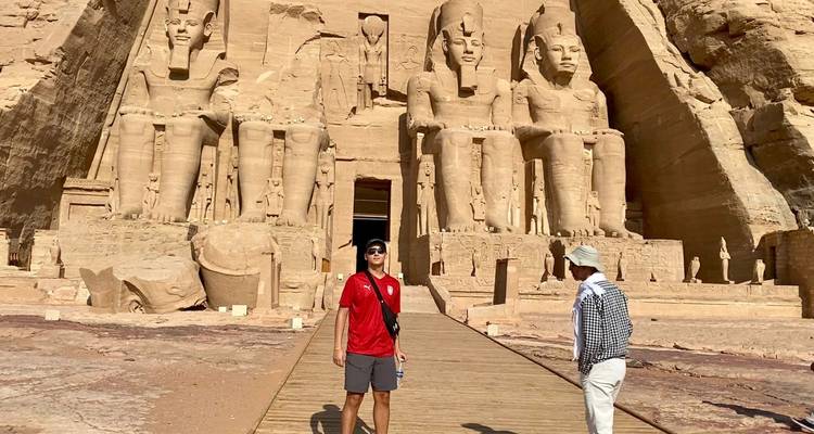 Des touristes devant de grandes statues assises de pharaons.
