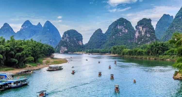 River running through green mountain landscape with boats.