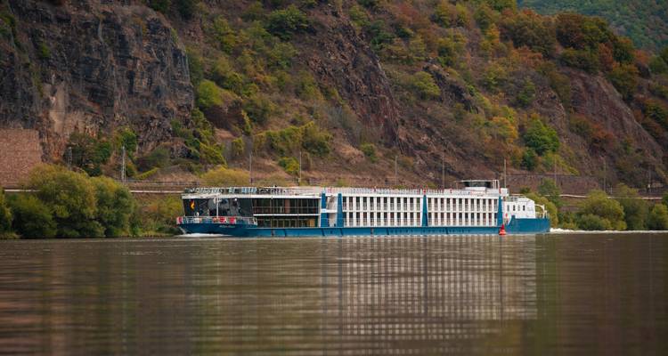 Navire de croisière naviguant le long de falaises rocheuses escarpées couvertes de feuillage d'automne.