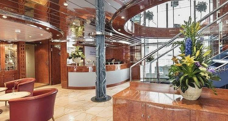 Espace de réception de navire de croisière avec boiseries, sols en marbre et fleurs fraîches.