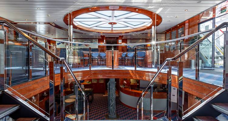 Atrium ensoleillé sur un bateau fluvial avec des escaliers courbes et une verrière.