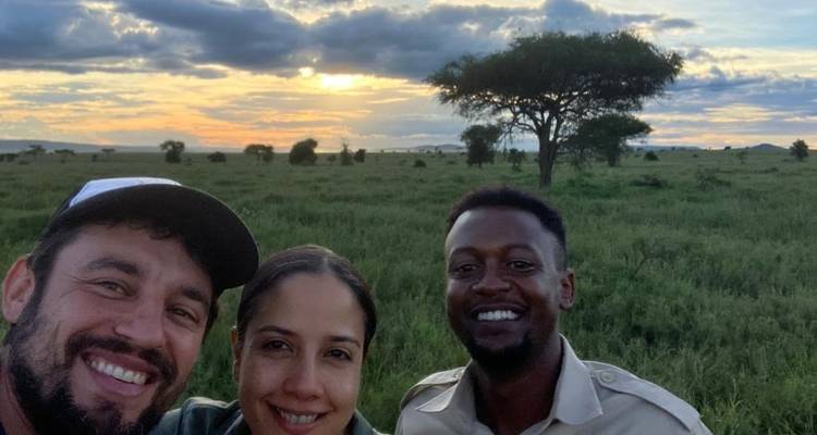 Groep mensen in een savanne-omgeving met zonsondergang.