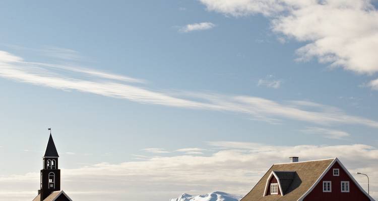 Una torre de iglesia y edificio bajo un cielo azul con nubes.