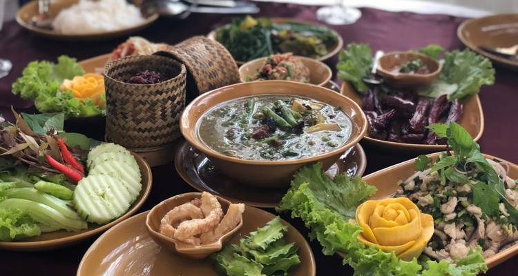 Repas traditionnel laotien avec divers plats présentés sur une table.