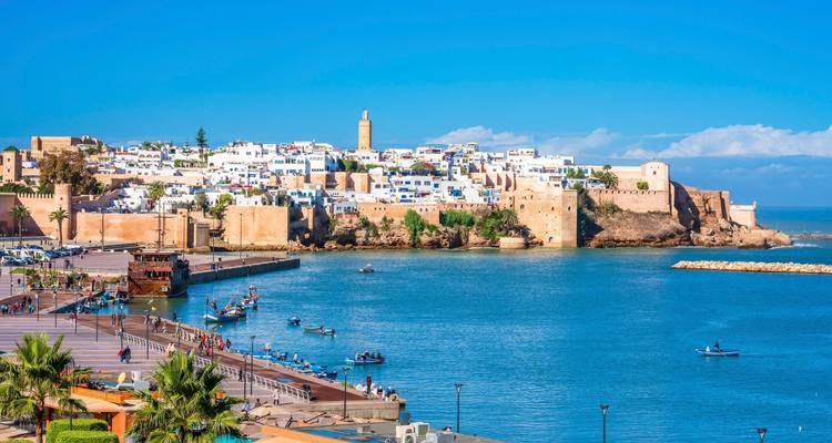 Meerblick-Panorama der Kasbah der Udayas in Rabat und der weiß gekalkten Medina-Mauern, die sich im ruhigen blauen Wasser spiegeln.