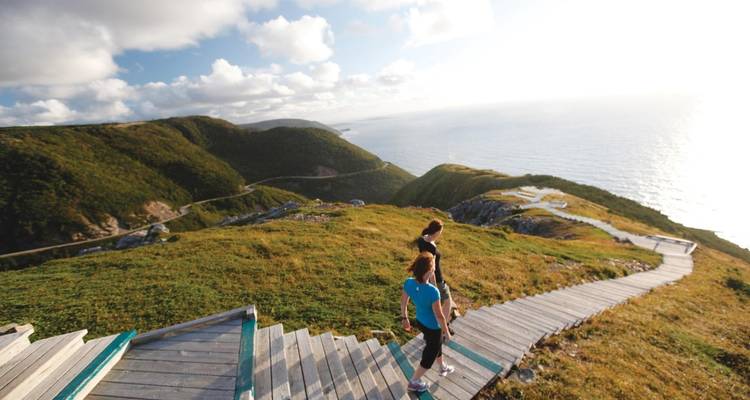 Menschen, die auf einem Steg gehen und auf Meeresklippen blicken.