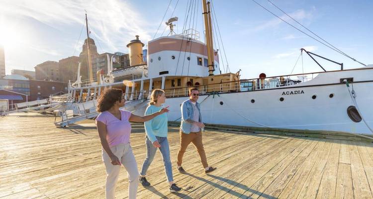 Gruppe geht entlang eines Hafens mit einem angedockten Schiff.