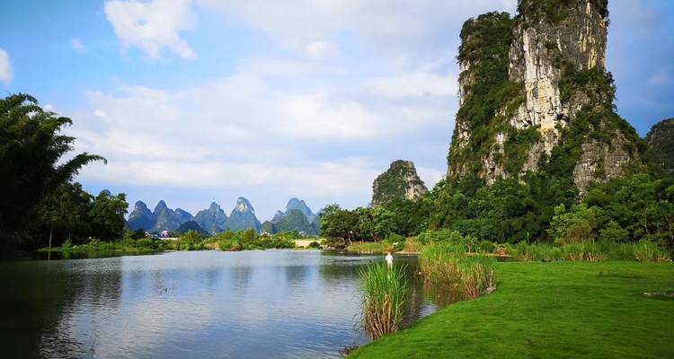 Malerische Karstgebirgslandschaft mit See und üppigem Grün.
