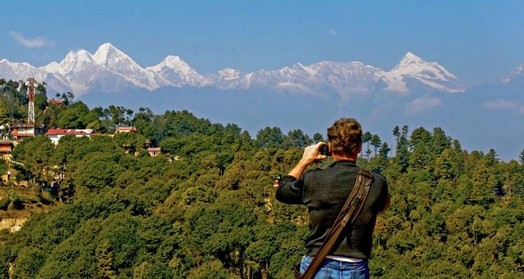 Une personne photographie une vue panoramique de montagnes enneigées.