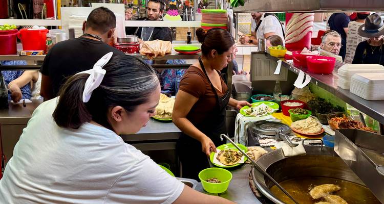 Personnel préparant de la nourriture dans un restaurant de marché local animé.