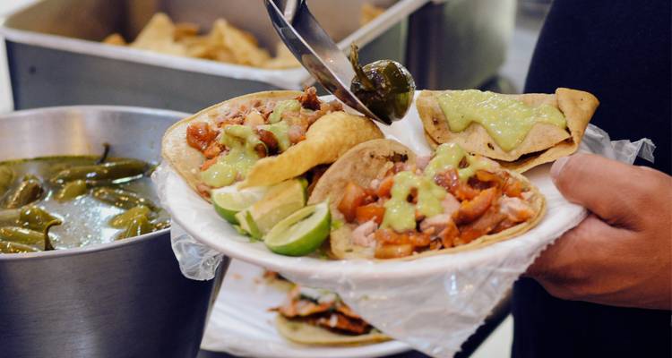 Un plato de tacos servido con lima y salsa.