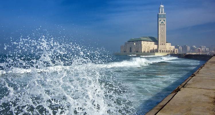Mosquée en bord de mer avec des vagues qui s'écrasent contre le rivage.