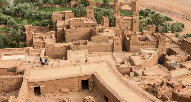 Perspectiva aérea del ksar fortificado de tierra de Ait Benhaddou rodeado de exuberantes palmeras datileras y llanura desértica.