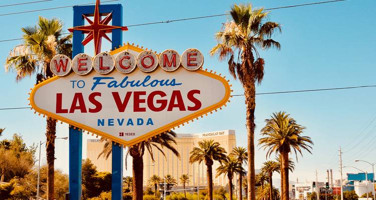 Panneau emblématique « Bienvenue au Fabuleux Las Vegas » encadré par des palmiers sous un ciel lumineux.