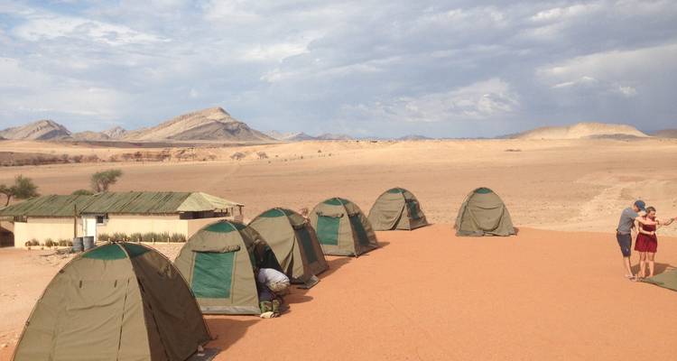 Menschen und Zelte auf einem Wüstencampingplatz.