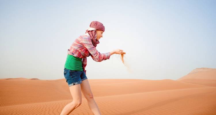 Personne jouant avec le sable dans le désert.