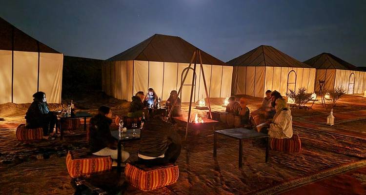 Des gens rassemblés autour d'un feu de camp sous un ciel étoilé.